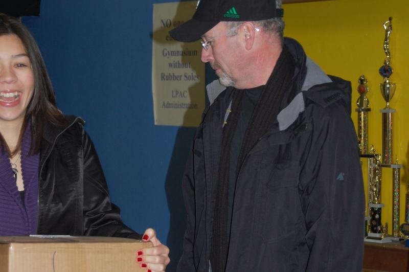 Un hombre recibe una gran caja de cartón con donaciones dentro de la oficina del programa.