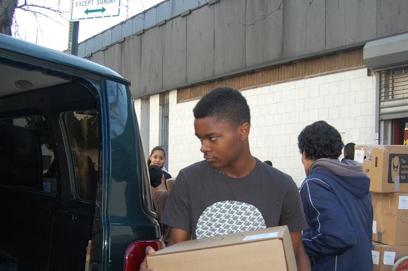 Un niño lleva una caja de cartón con donaciones hacia la parte trasera abierta de una camioneta.