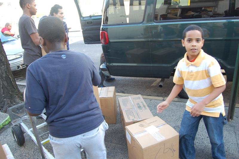 Dos niños llevan cajas de cartón hasta una camioneta durante una colecta de donaciones.