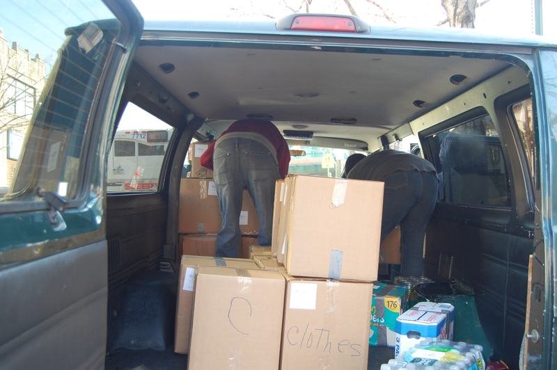 El interior de una camioneta llena de cajas de donaciones rotuladas y botellas de agua.