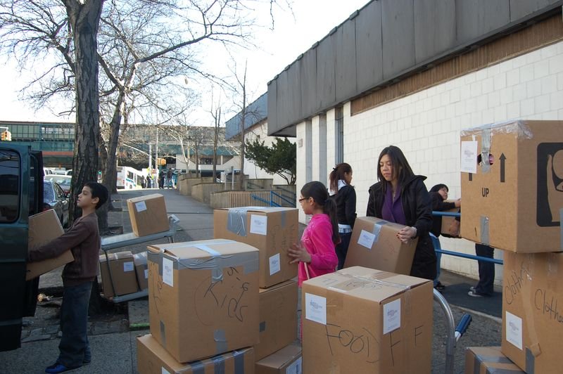 Voluntarios y mentoreados apilan cajas de alimentos donados en una calle del Bronx.