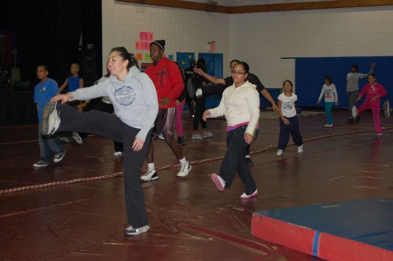 Mentores y mentoreados participan en un juego grupal en el gimnasio de la escuela.
