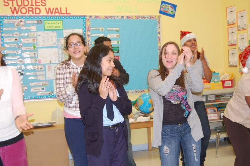 Dos mentoreadas aplauden y ríen durante la fiesta navideña del aula.