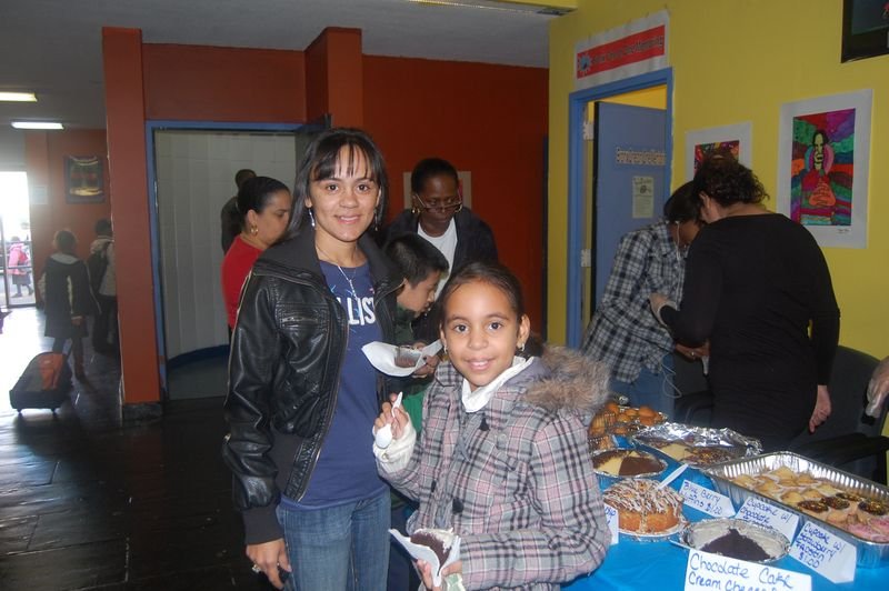 Mentoreados y familias se reúnen alrededor de la mesa de refrigerios en una celebración de BOOM.