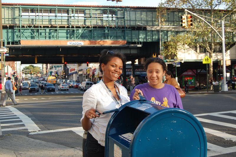 Una mentora y su mentoreada repintan un buzón en una esquina del Bronx.
