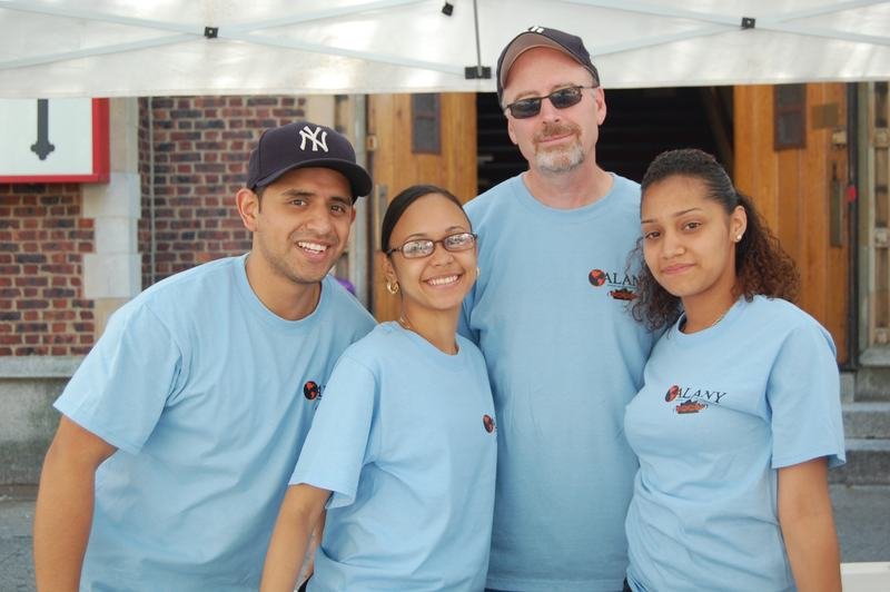 Cuatro integrantes del equipo de difusión de ALANY con camisetas azules en una calle del Bronx.